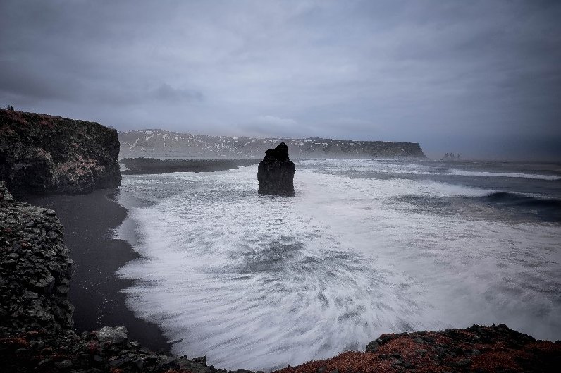 Onde attorno a uno scoglio sotto un cielo scuro